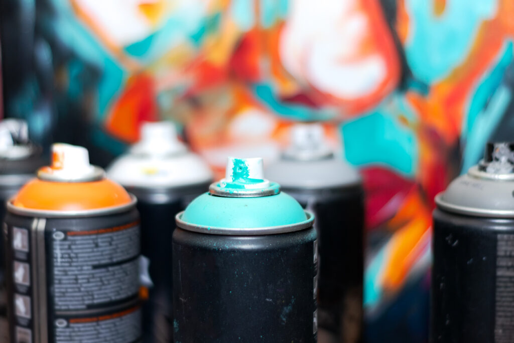 spray cans with orange and turquoise paint for graffiti close up against the background of the painted picture